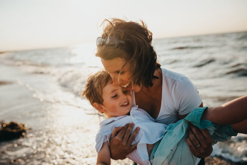 Fruchtbarkeit: Mutter mit Sohn auf dem Arm am Strand